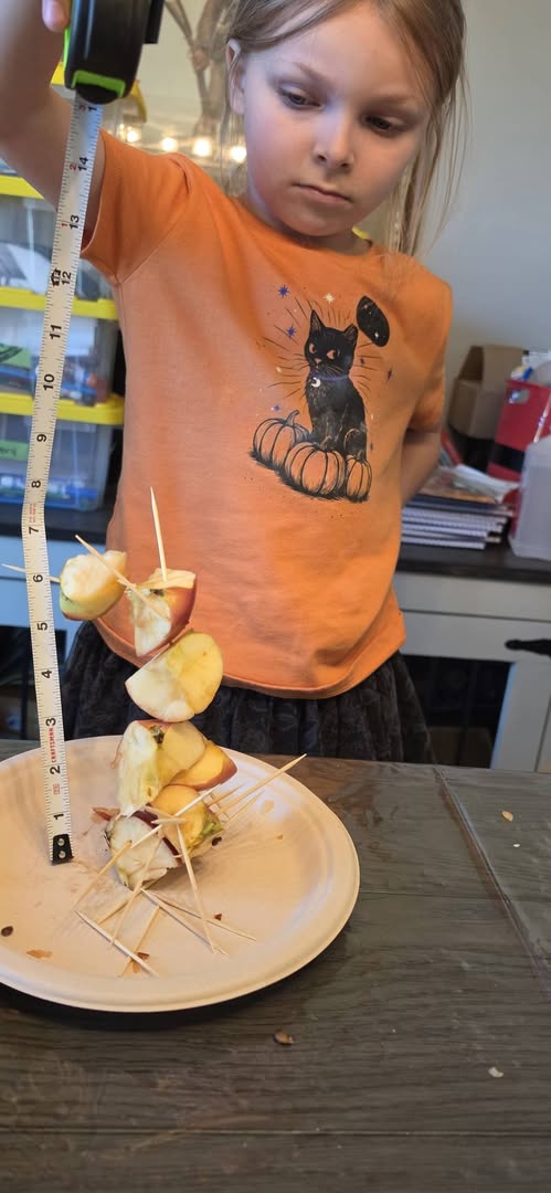 Student measuring a tower of apples and toothpicks